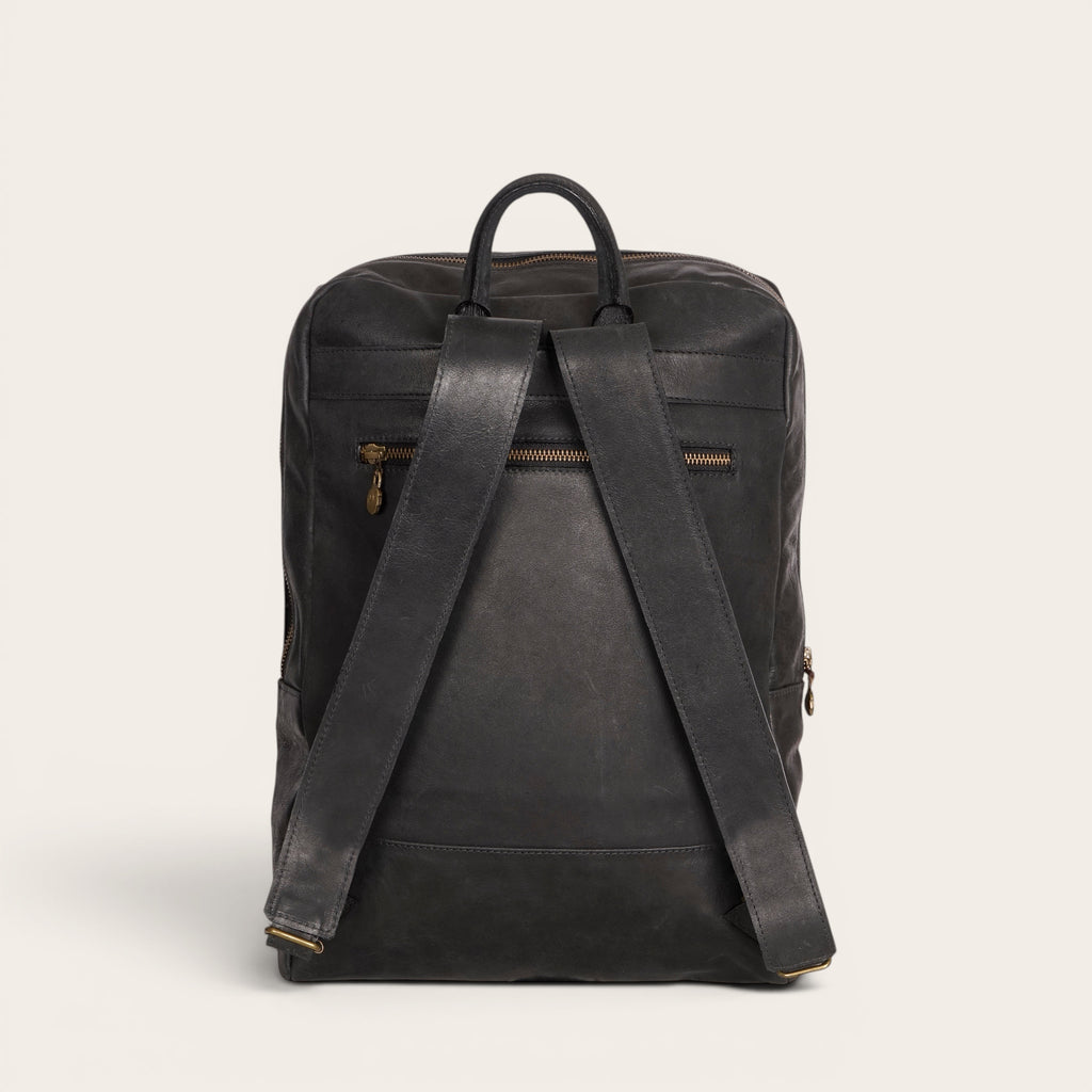 Mochila negra de cuero de vacuno OLKI con compartimento acolchado para portátil y 15 litros de capacidad.