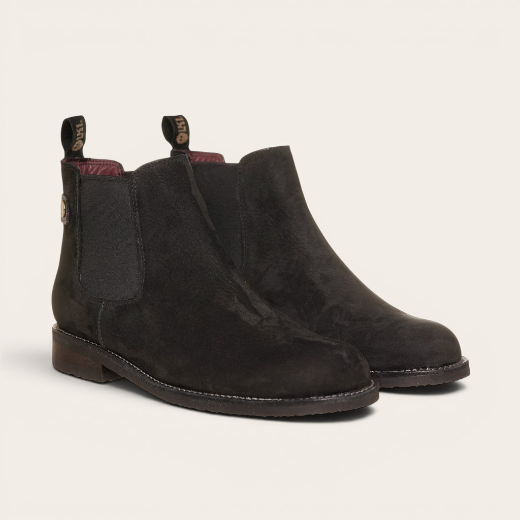 Botín chelsea negro de cuero nobuk de OLKI, diseño urbano sin cordones con elásticos laterales y tiradores.