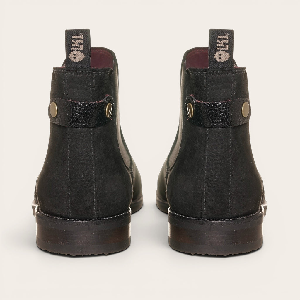 Botín chelsea negro de cuero nobuk de OLKI, diseño urbano sin cordones con elásticos laterales y tiradores.