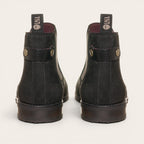 Botín chelsea negro de cuero nobuk de OLKI, diseño urbano sin cordones con elásticos laterales y tiradores.