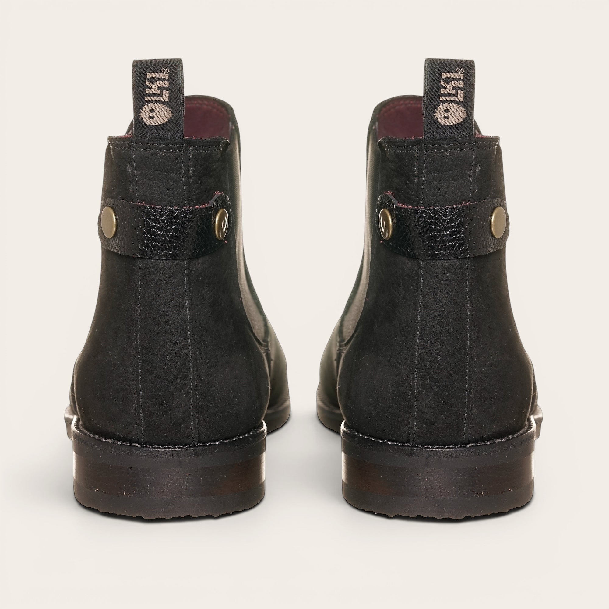 Botín chelsea negro de cuero nobuk de OLKI, diseño urbano sin cordones con elásticos laterales y tiradores.