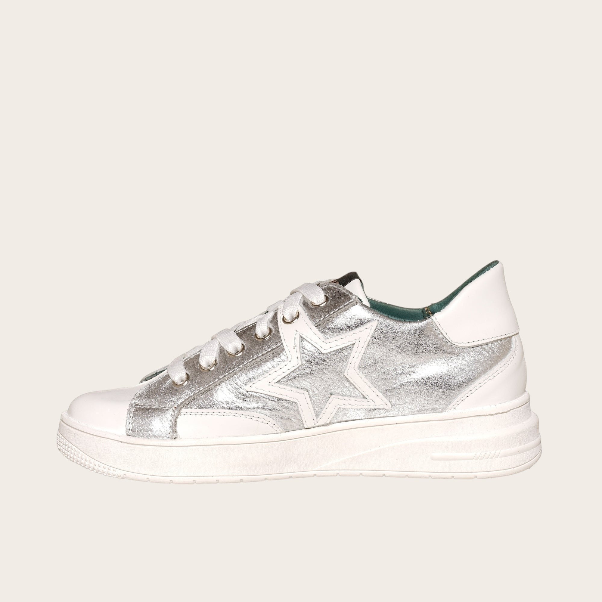 Zapatilla OLKI Loica blanca con detalle de estrella plateada, cordones blancos y planta de caucho.