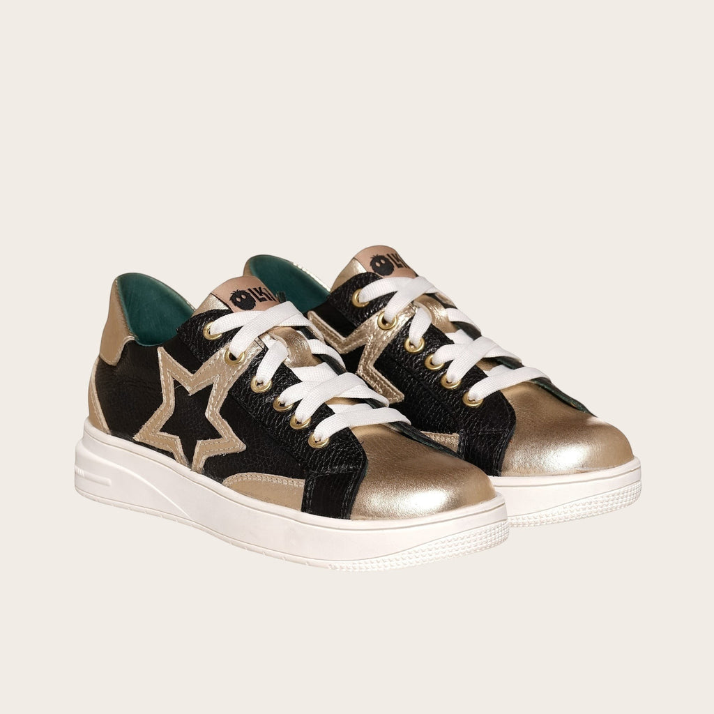 Zapatilla OLKI Loica negra y dorada con detalle de estrella, cordones blancos y planta de caucho.