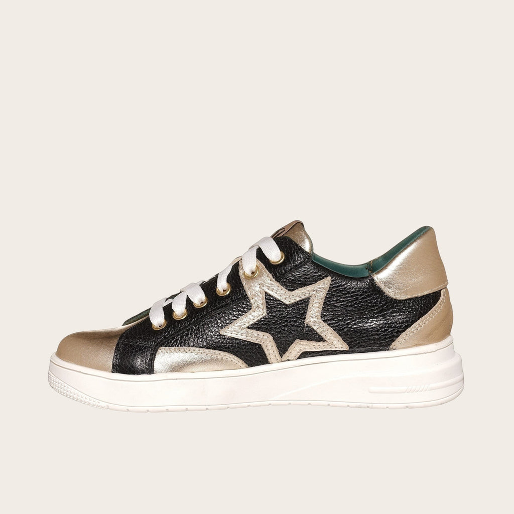 Zapatilla OLKI Loica negra y dorada con detalle de estrella, cordones blancos y planta de caucho.