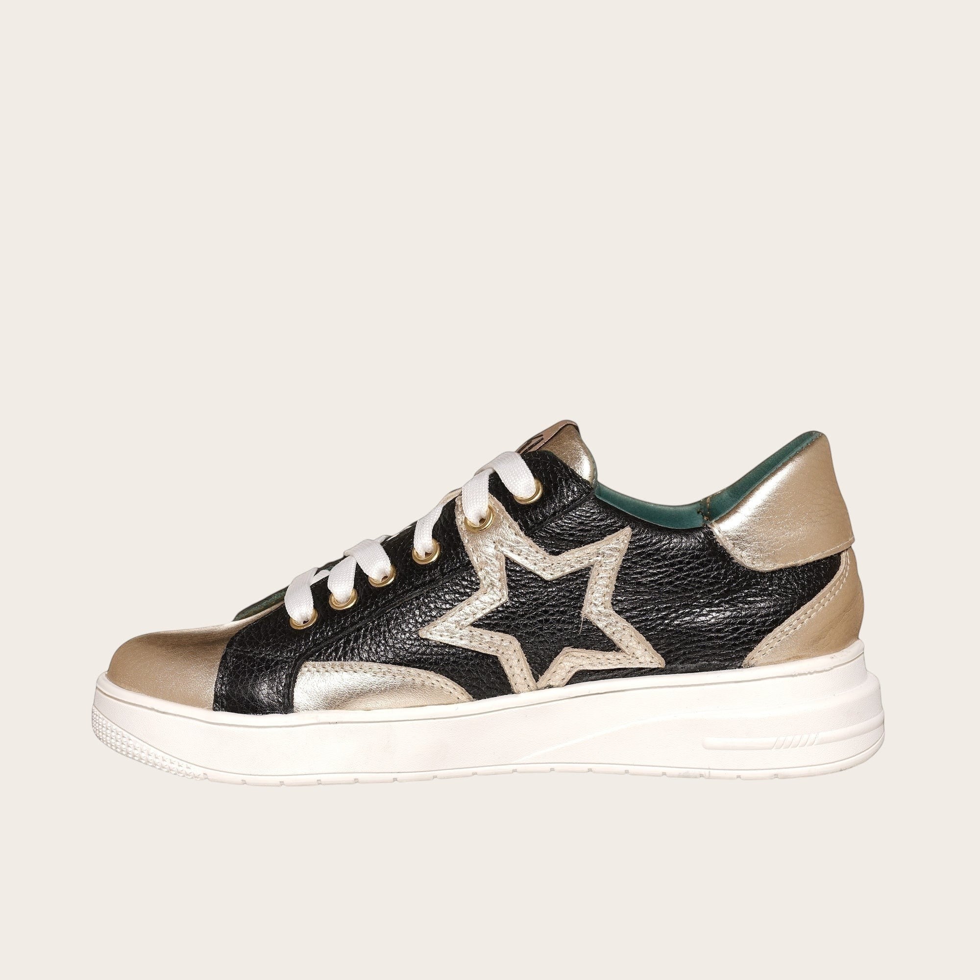 Zapatilla OLKI Loica negra y dorada con detalle de estrella, cordones blancos y planta de caucho.