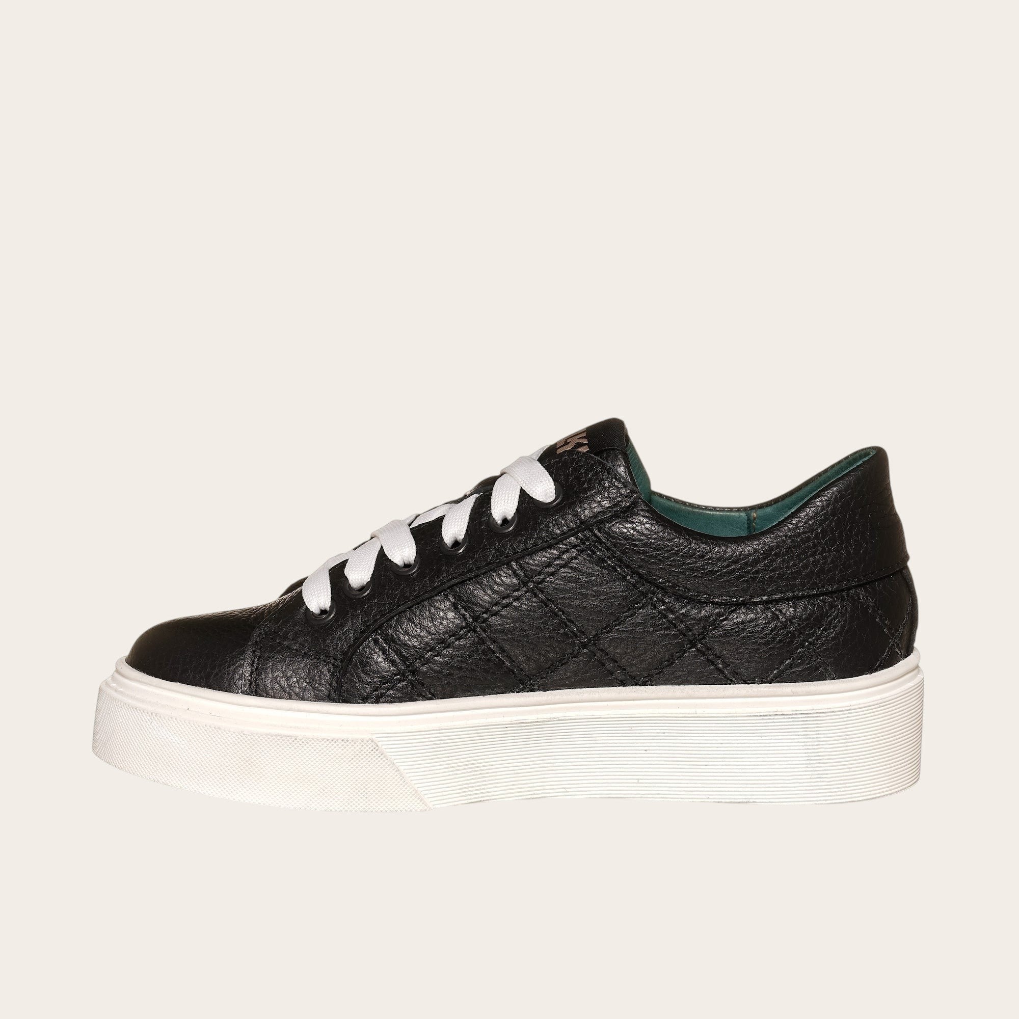 Zapatilla OLKI Real negra acolchada de piel con cordones blancos y planta de plataforma blanca.