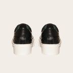 Zapatilla OLKI Real negra de cuero con acolchado lateral y planta blanca de plataforma.