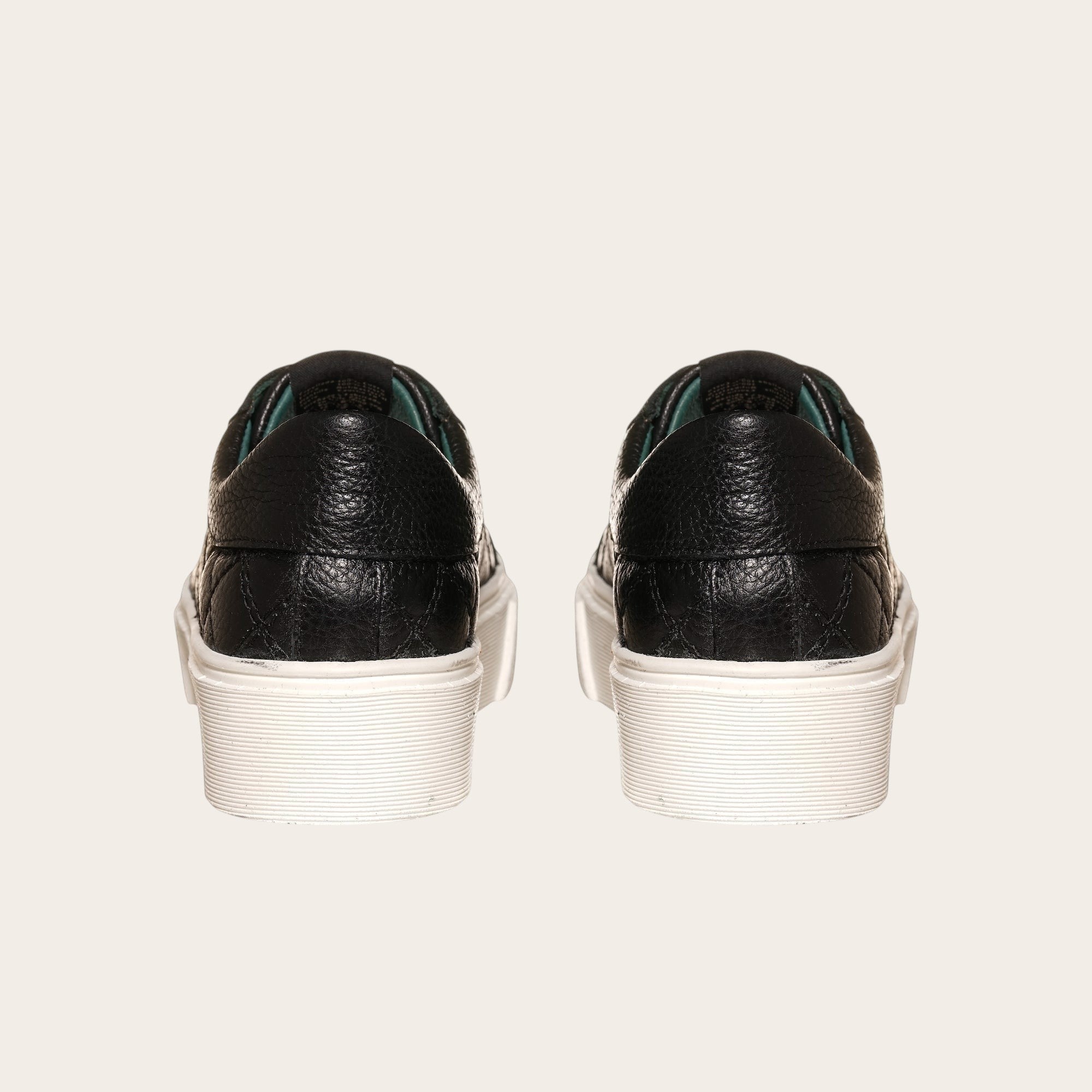 Zapatilla OLKI Real negra de cuero con acolchado lateral y planta blanca de plataforma.