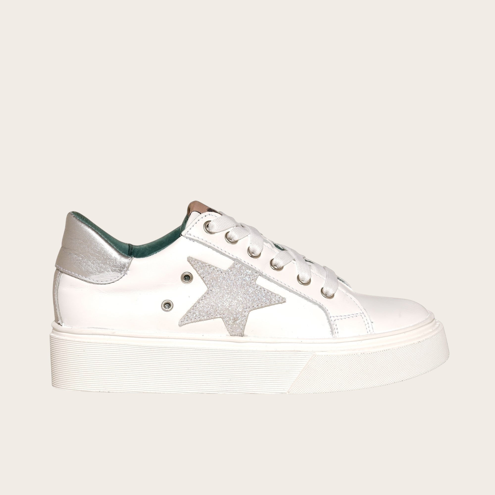 Zapatilla OLKI Tricahue blanca con detalle de estrella plateada brillante y planta de plataforma blanca.