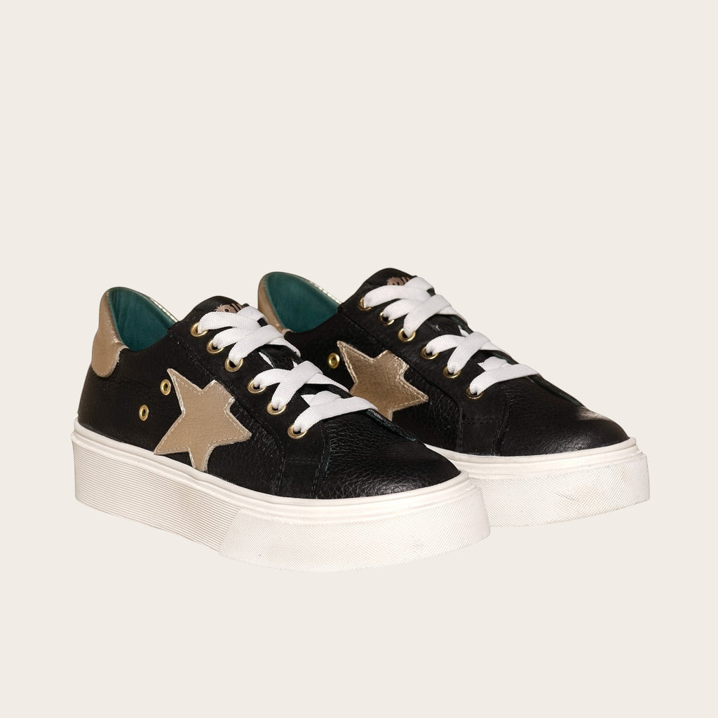 Zapatilla OLKI Tricahue negra con detalle de estrella dorada, cordones blancos y planta de plataforma blanca.
