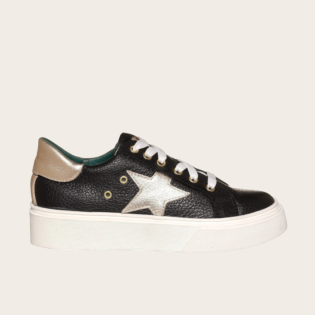 Zapatilla OLKI Tricahue negra con detalle de estrella dorada, cordones blancos y planta de plataforma blanca.