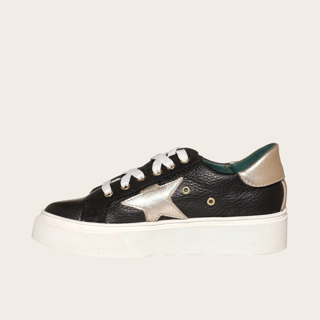 Zapatilla OLKI Tricahue negra con detalle de estrella dorada, cordones blancos y planta de plataforma blanca.