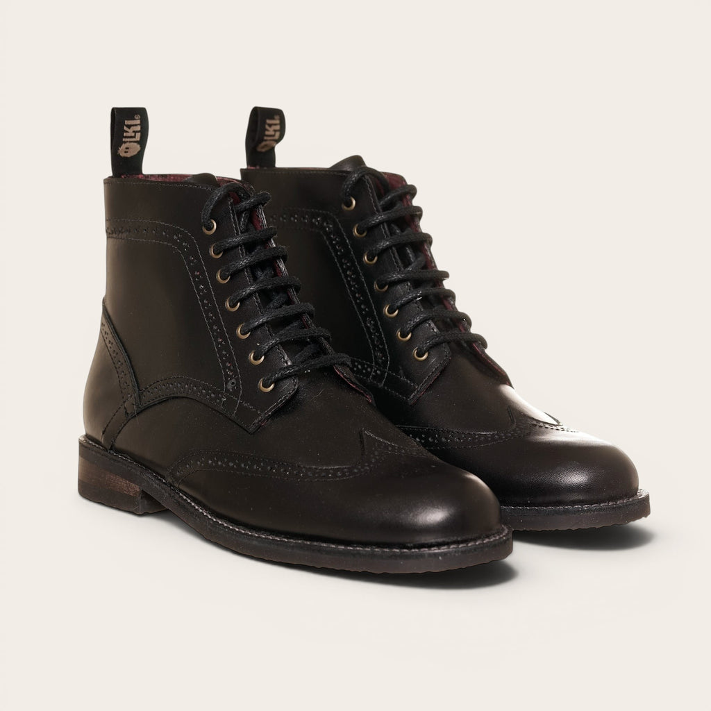 Botín de cuero negro OLKI con cordones, suela negra y detalles brogue. Diseño urbano y elegante.