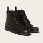 Botín de cuero negro OLKI con cordones, suela negra y detalles brogue. Diseño urbano y elegante.