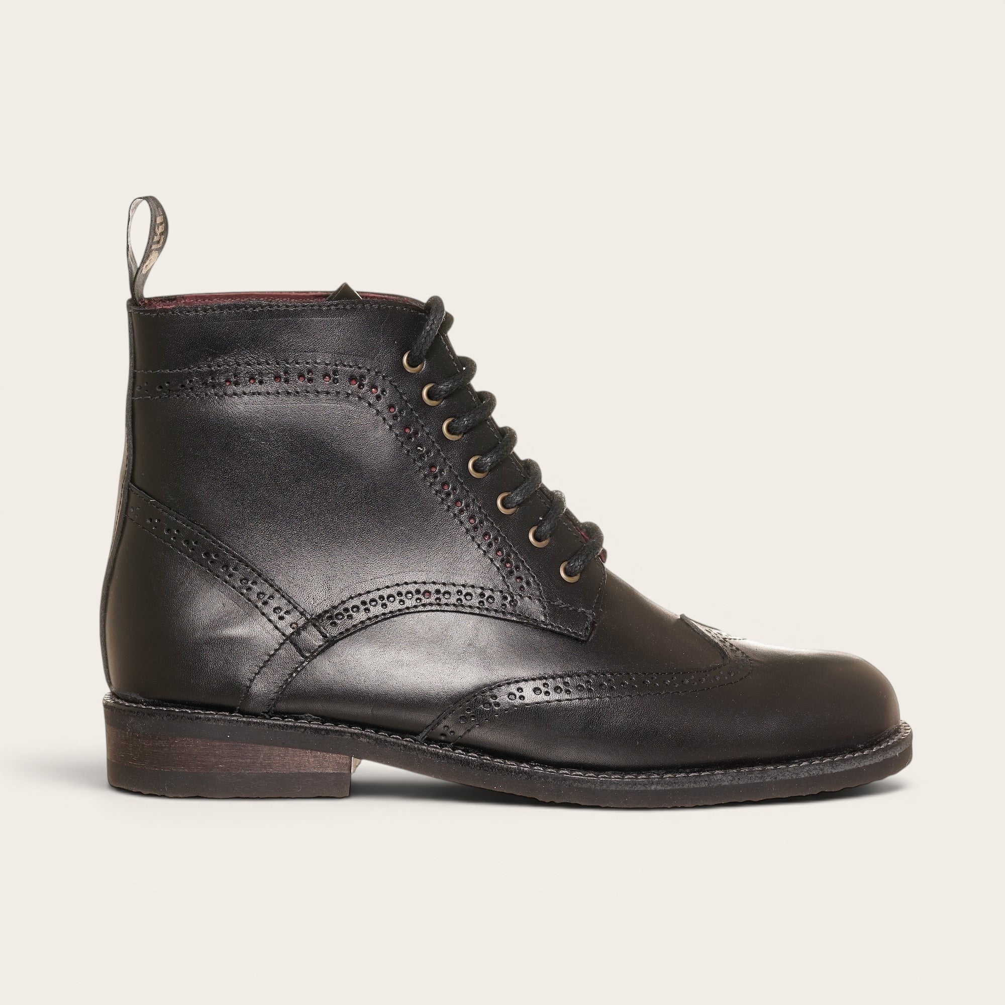 Botín de cuero negro OLKI con cordones, suela negra y detalles brogue. Diseño urbano y elegante.