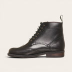 Botín de cuero negro OLKI con cordones, suela negra y detalles brogue. Diseño urbano y elegante.