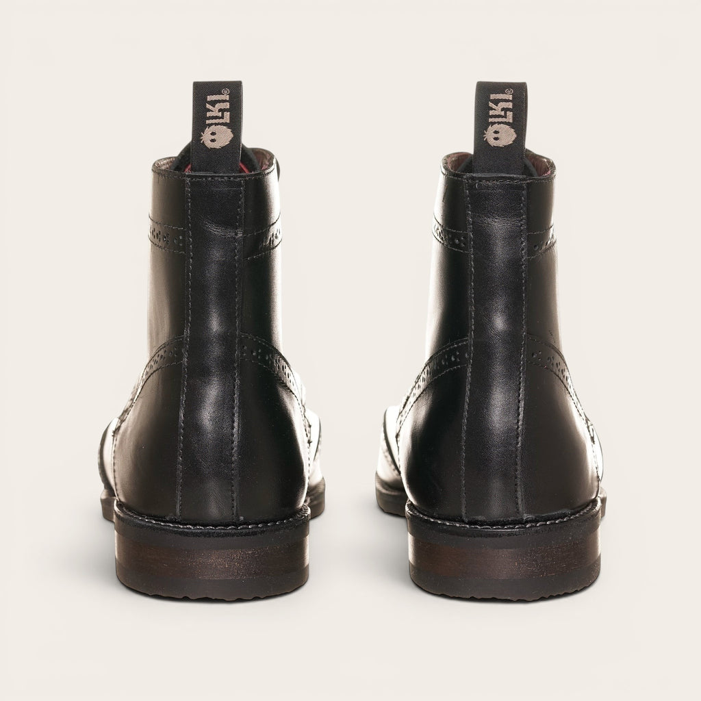 Botín de cuero negro OLKI con cordones, suela negra y detalles brogue. Diseño urbano y elegante.