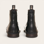 Botín de cuero negro OLKI con cordones, suela negra y detalles brogue. Diseño urbano y elegante.