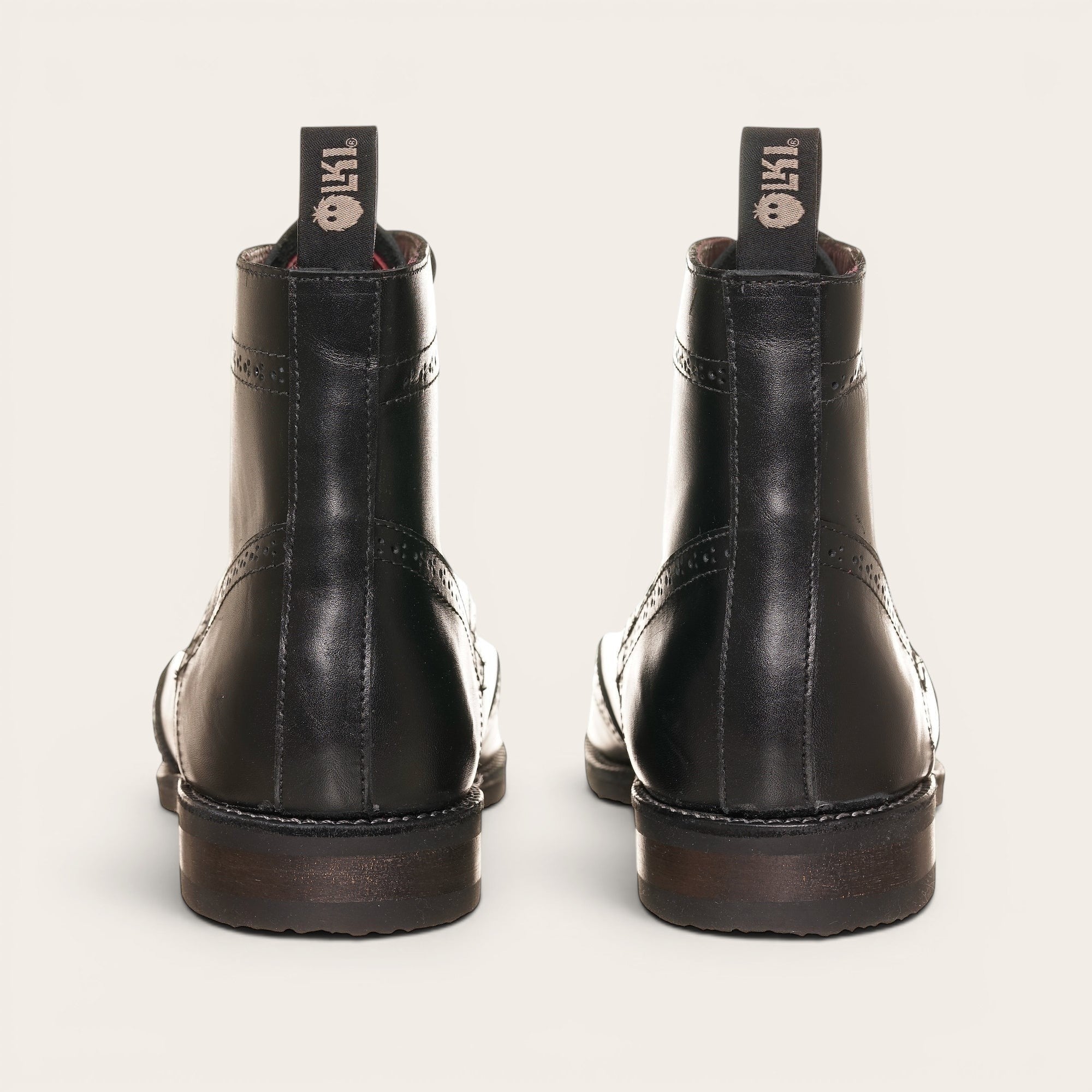 Botín de cuero negro OLKI con cordones, suela negra y detalles brogue. Diseño urbano y elegante.