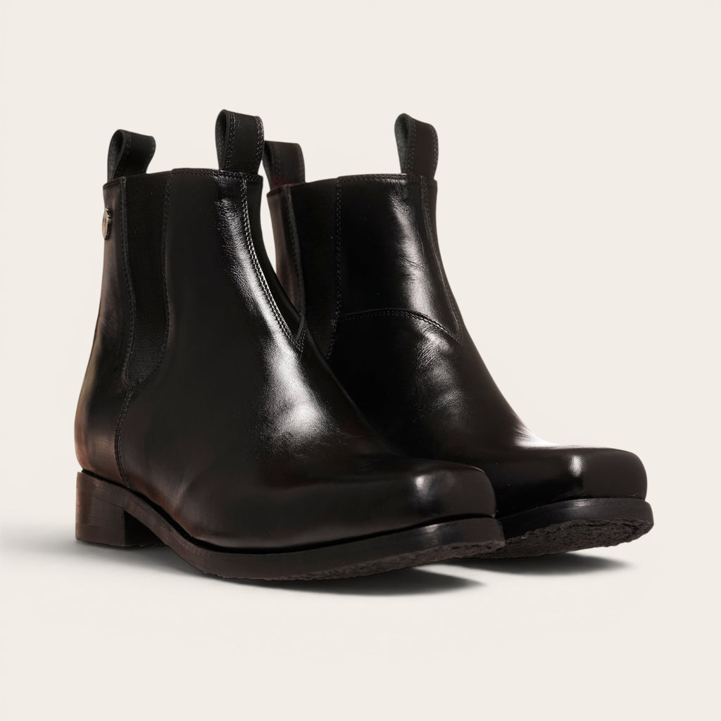 Botines negros de cuero liso OLKI Llanquihue con paneles elásticos laterales y caña alta.