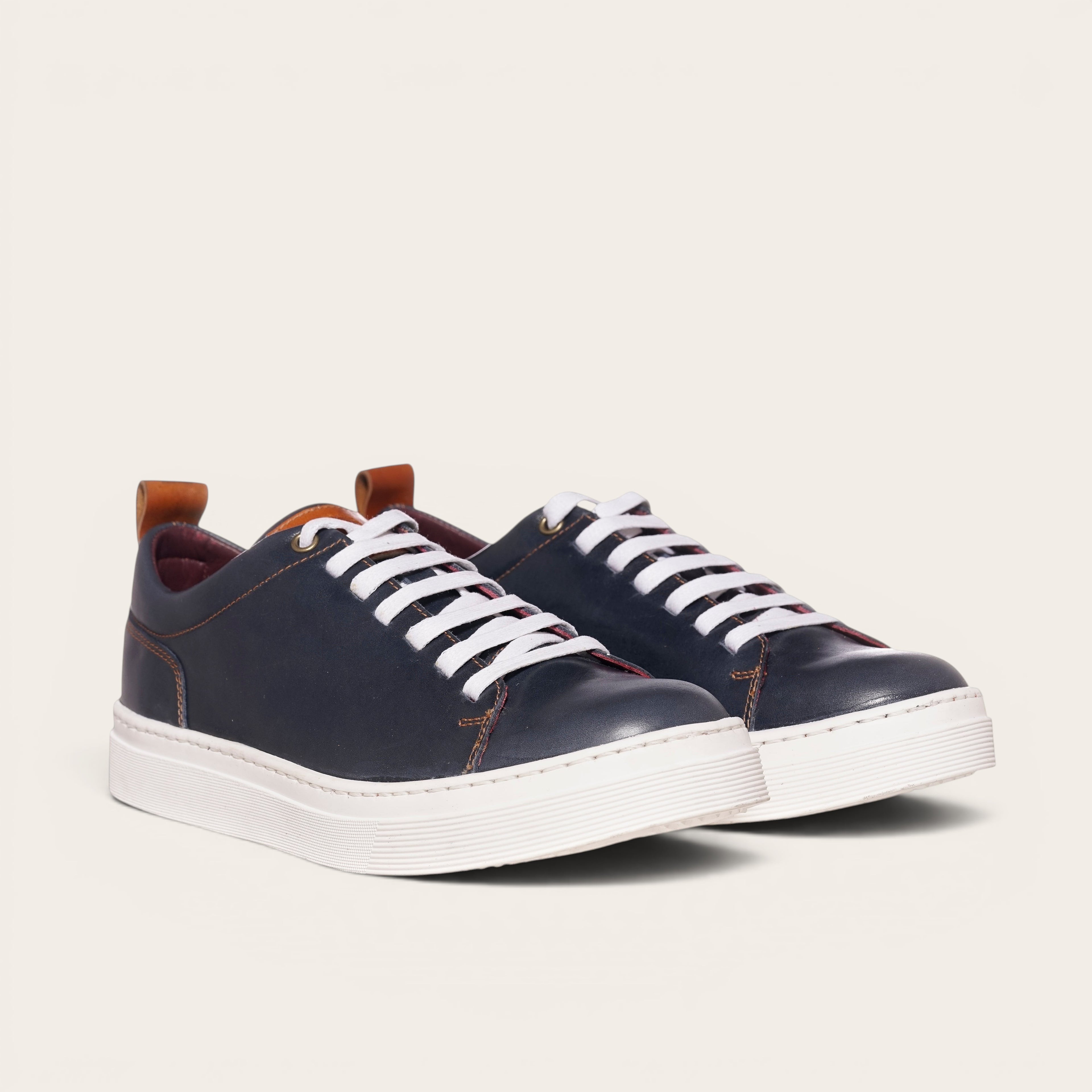 Zapatilla versátil OLKI Calán azul marino de cuero con cordones blancos y planta blanca.