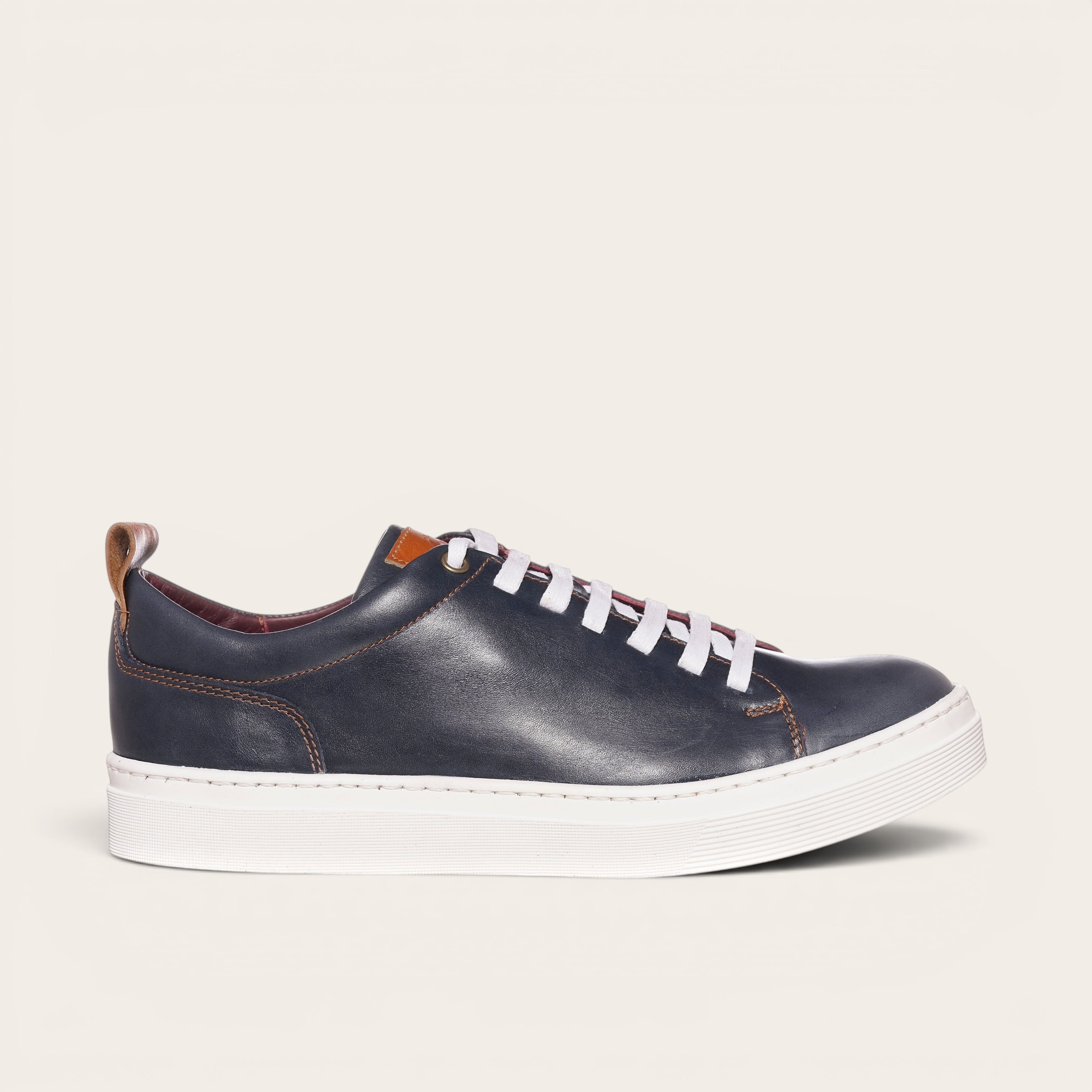 Zapatilla OLKI Calán azul marino de cuero con cordones blancos y planta blanca.