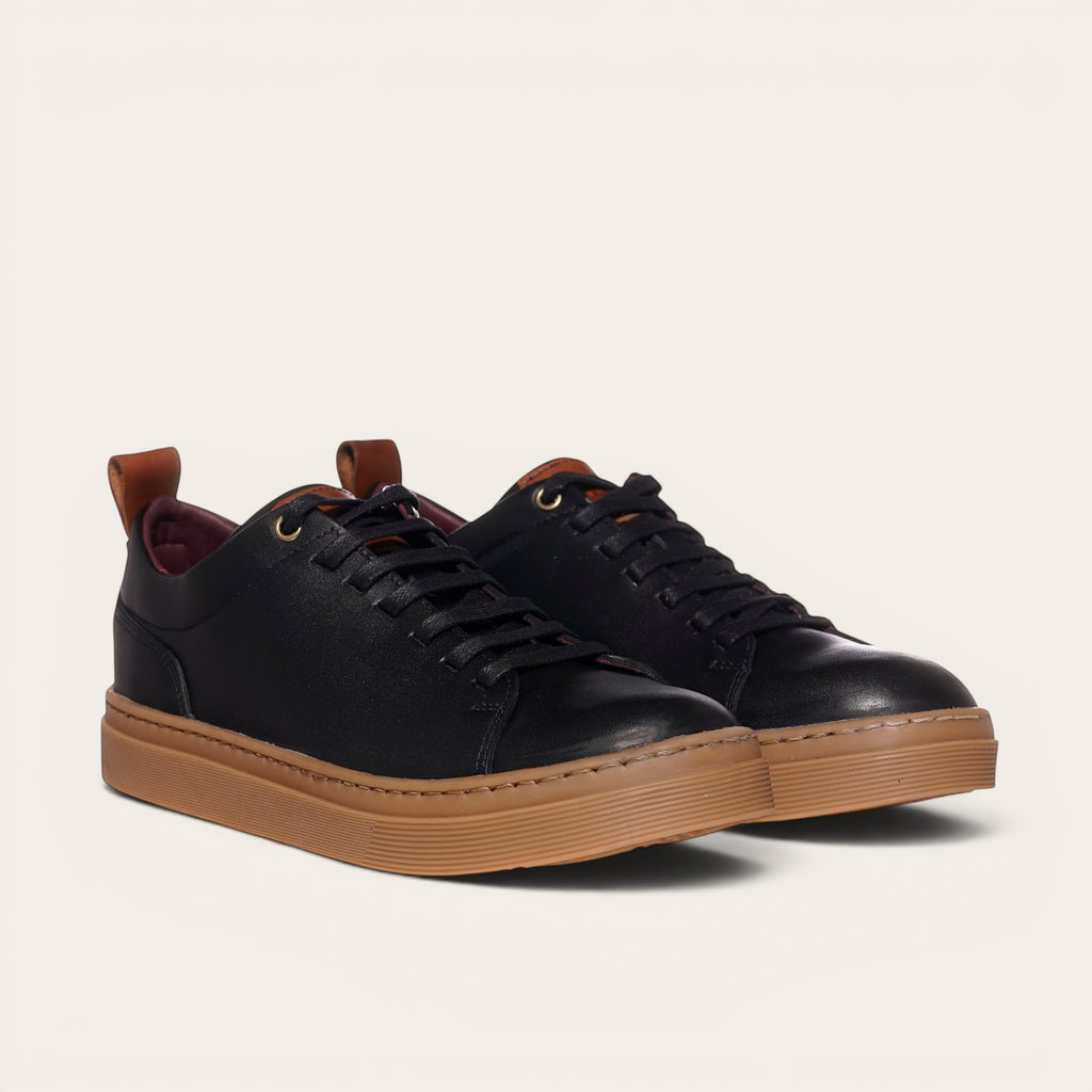 Zapatilla Calán negra de cuero con planta de caucho color cristal y cordones a juego. Diseño minimalista.