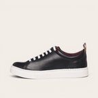 Zapatilla OLKI Calán negra de cuero con cordones blancos y planta blanca. Diseño artesanal chileno.