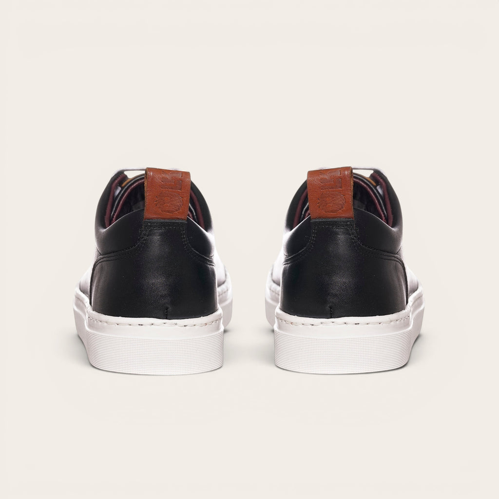 Zapatilla Calán negra de cuero con planta blanca y detalle de cuero en el talón. Marca OLKI.
