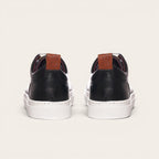 Zapatilla Calán negra de cuero con planta blanca y detalle de cuero en el talón. Marca OLKI.