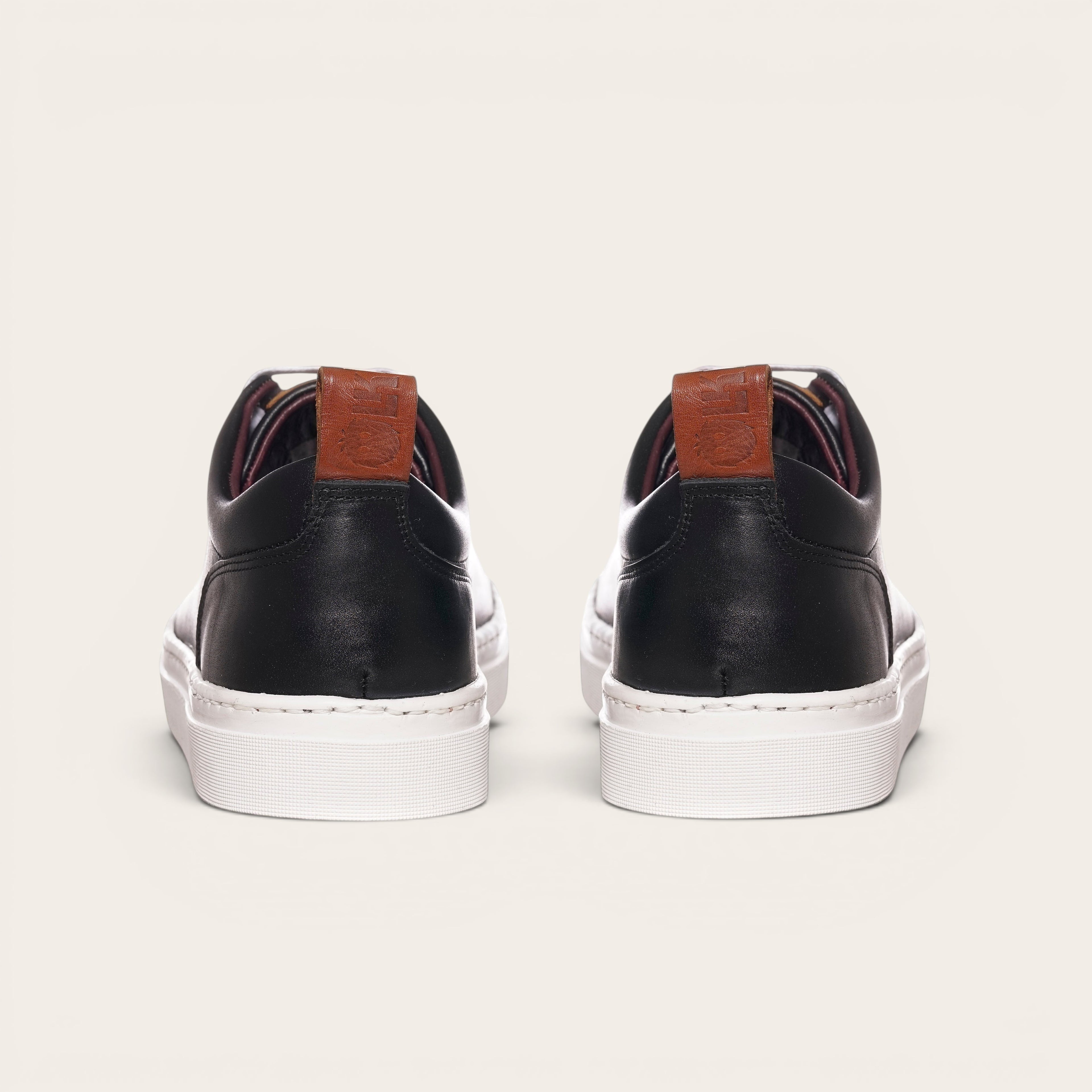 Zapatilla Calán negra de cuero con planta blanca y detalle de cuero en el talón. Marca OLKI.