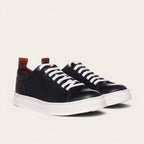 Zapatilla Calán de OLKI en cuero negro con cordones blancos y planta blanca. Diseño artesanal.