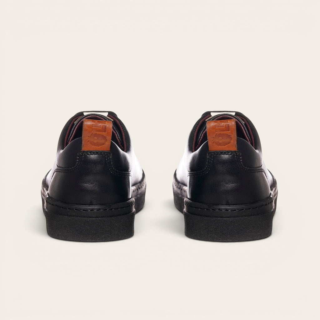 Zapatilla Calán negra de cuero de vacuno con cordones de algodón encerado y planta de caucho antideslizante. OLKI.