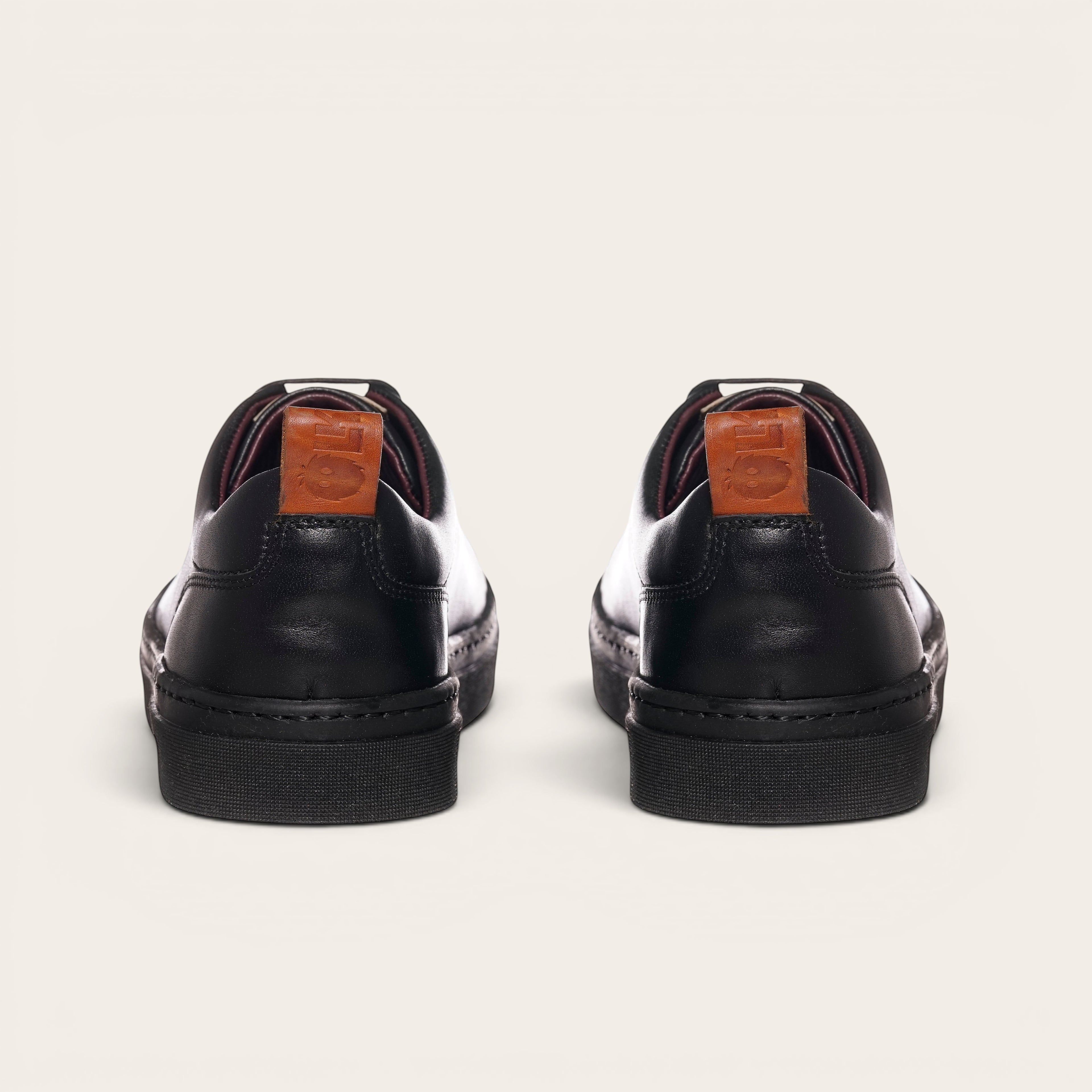 Zapatilla Calán negra de cuero de vacuno con cordones de algodón encerado y planta de caucho antideslizante. OLKI.