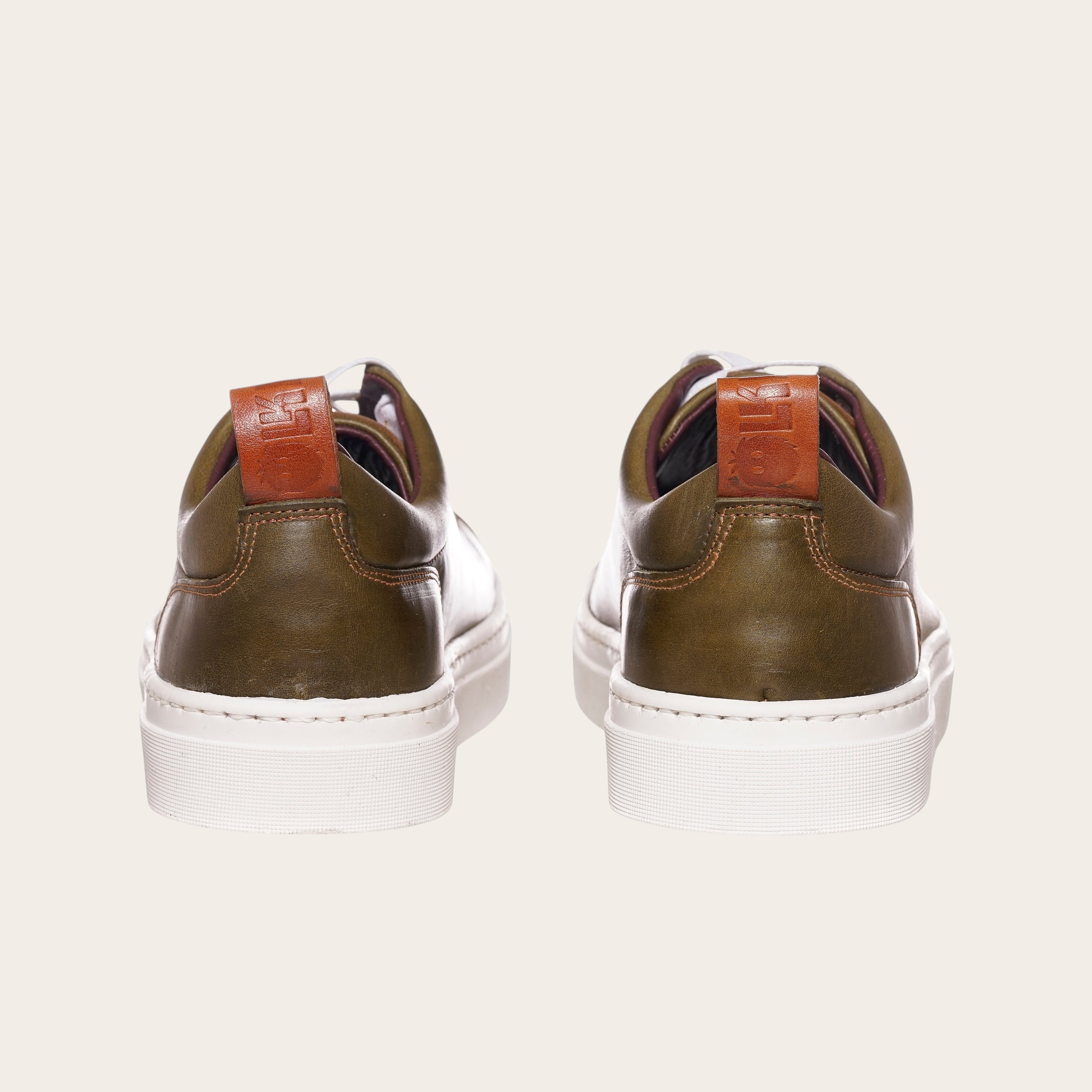 Zapatilla OLKI Calán verde musgo de cuero con planta blanca y detalle de cuero en el talón.