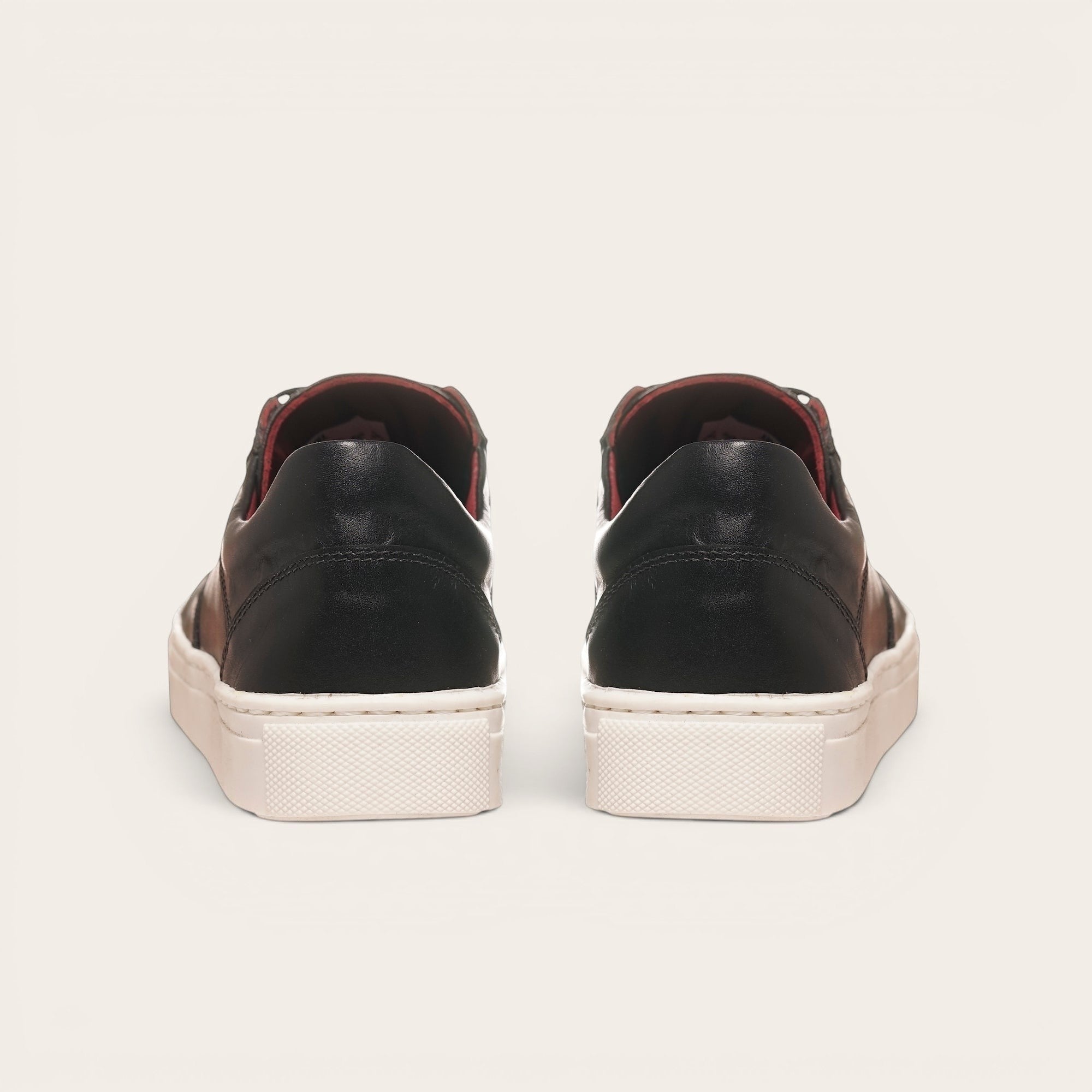 Zapatilla OLKI La Campana negra de cuero con planta blanca y forro burdeos. Diseño urbano minimalista.