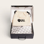 Zapatillas OLKI La Campana negras de cuero con forro burdeo y planta de caucho cristal, presentada en su caja con bolsa protectora.