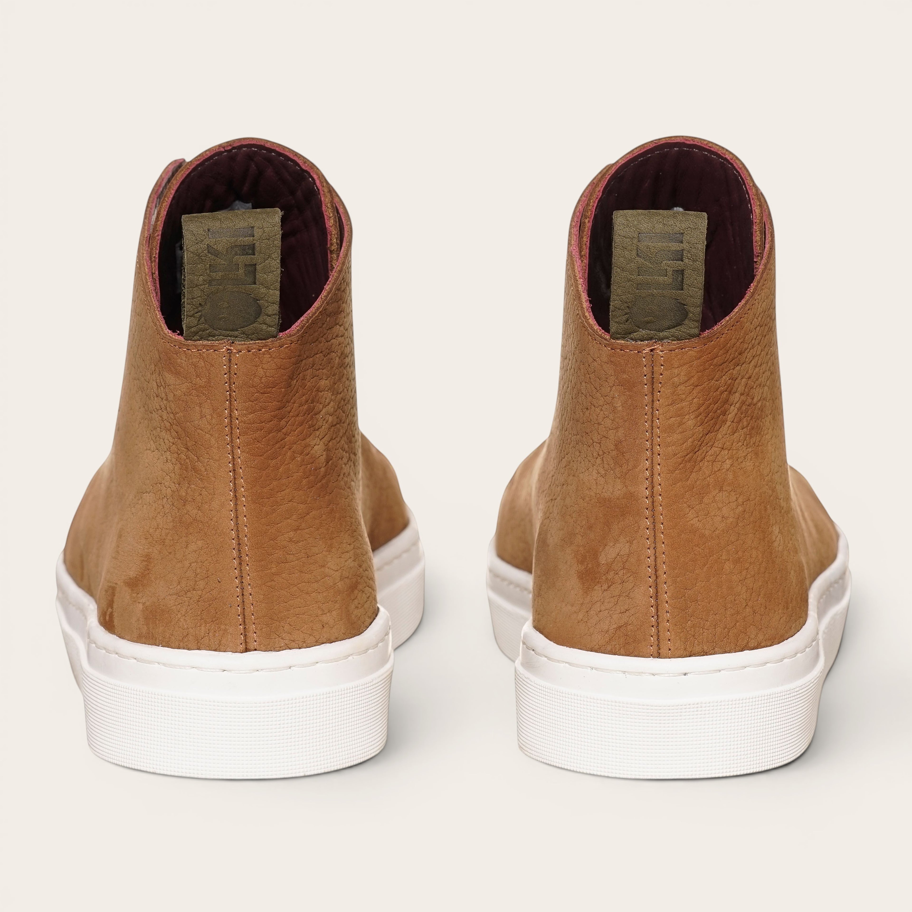 Zapatilla Manquehue de OLKI en cuero nobuk color avellana con cordones blancos y planta blanca de caucho. Diseño urbano.