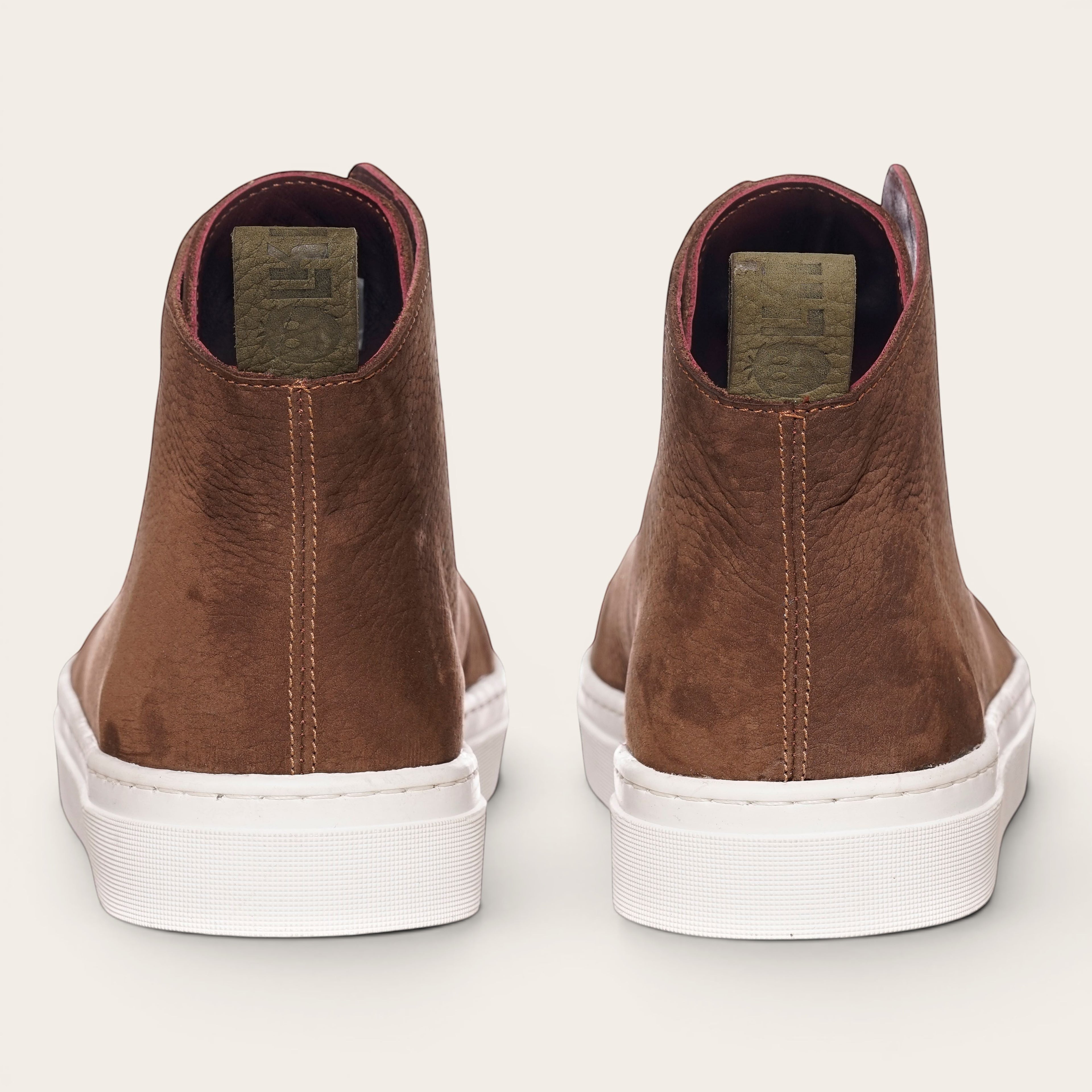 Zapatilla alta chocolate de cuero noburo con cordones de algodón encerado y planta blanca de caucho. OLKI.