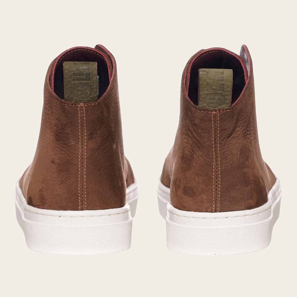 Zapatilla alta chocolate de cuero noburo con cordones de algodón encerado y planta blanca de caucho. OLKI.