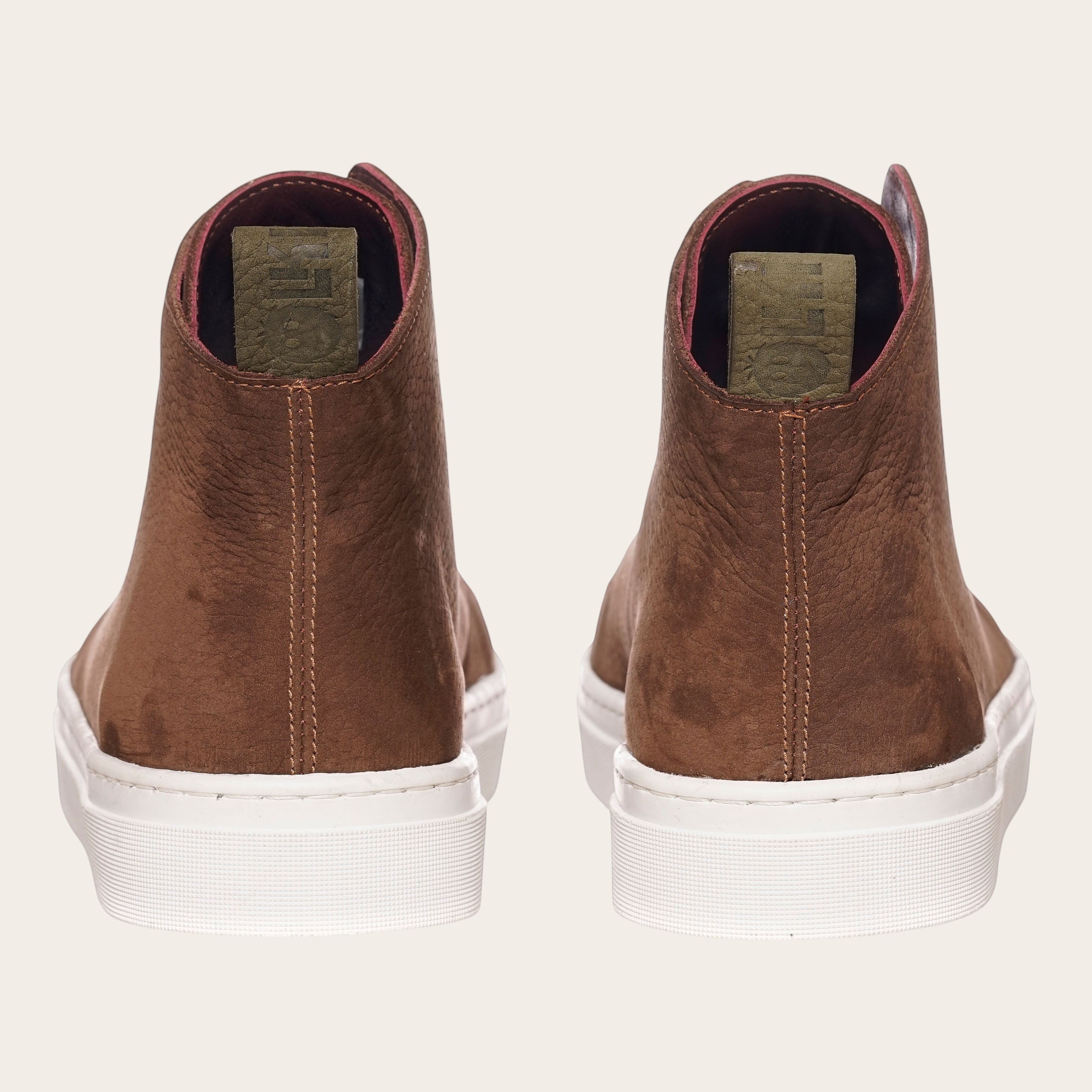 Zapatilla alta chocolate de cuero noburo con cordones de algodón encerado y planta blanca de caucho. OLKI.