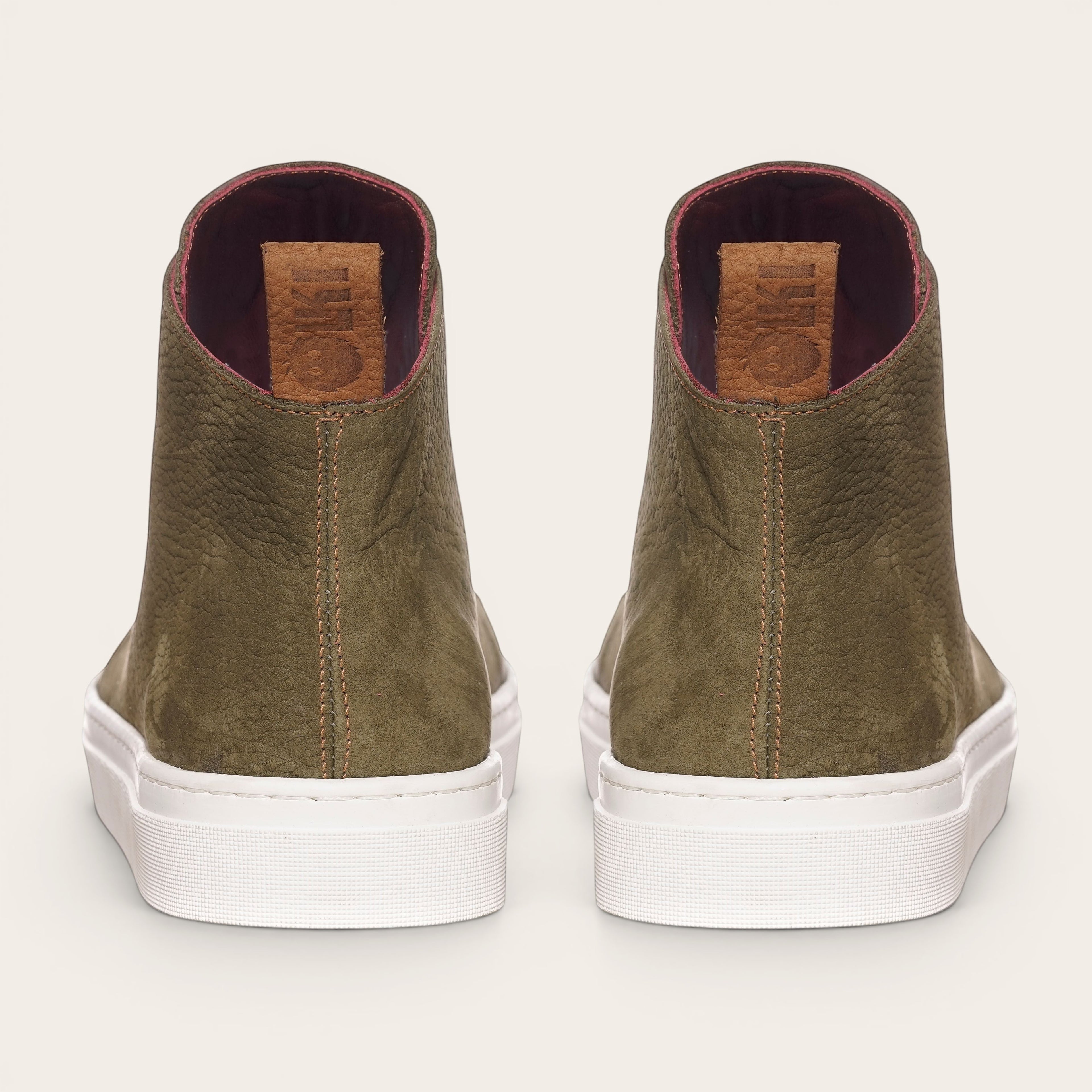 Zapatilla OLKI Manquehue verde musgo de cuero con cordones blancos y planta blanca gruesa. Diseño urbano.