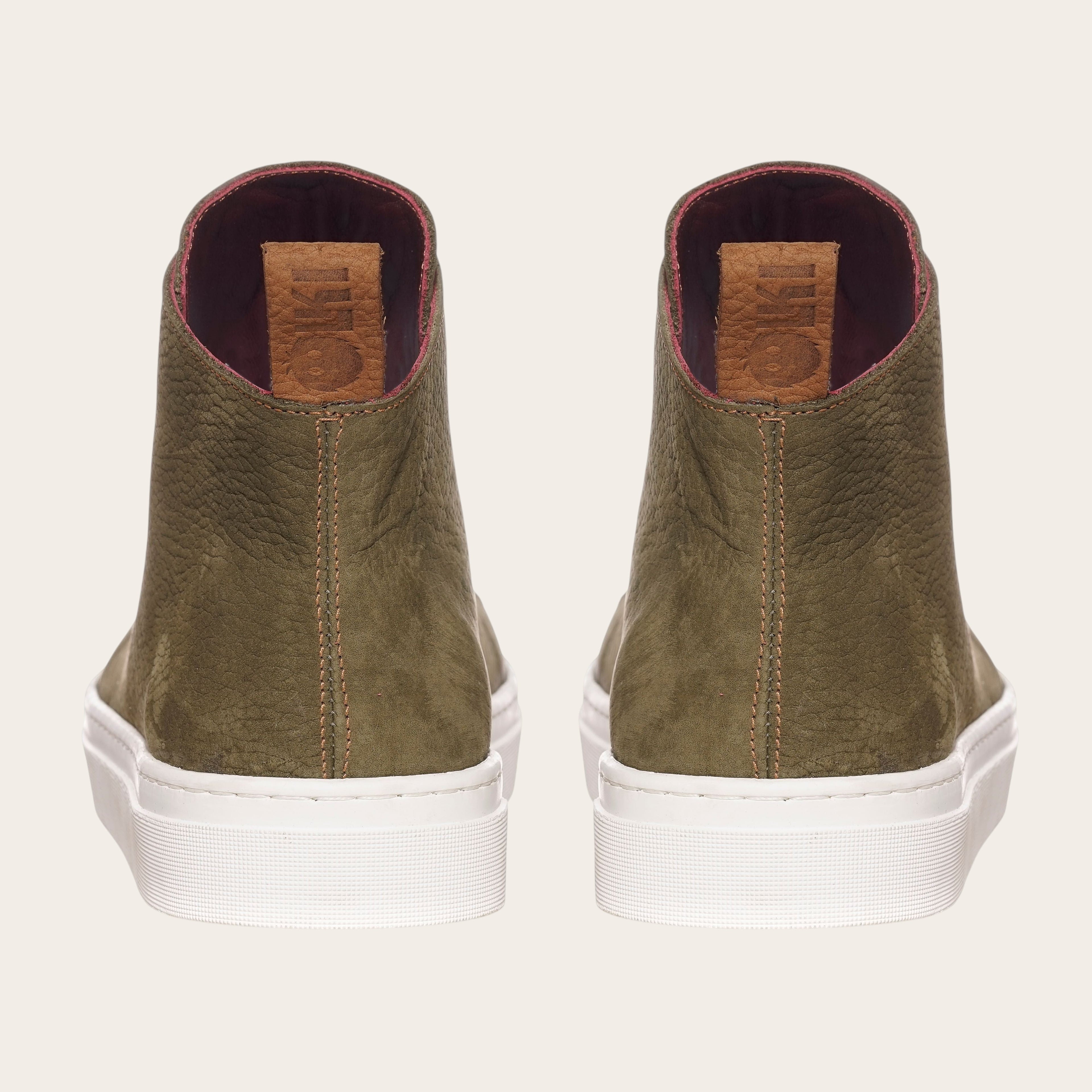 Zapatilla OLKI Manquehue verde musgo de cuero con cordones blancos y planta blanca gruesa. Diseño urbano.