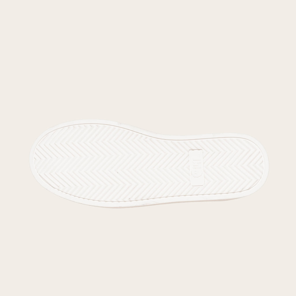 OLKI Zapatilla Nevado blanca planta de caucho antideslizante con patrón de espiga y logo. Diseño urbano.