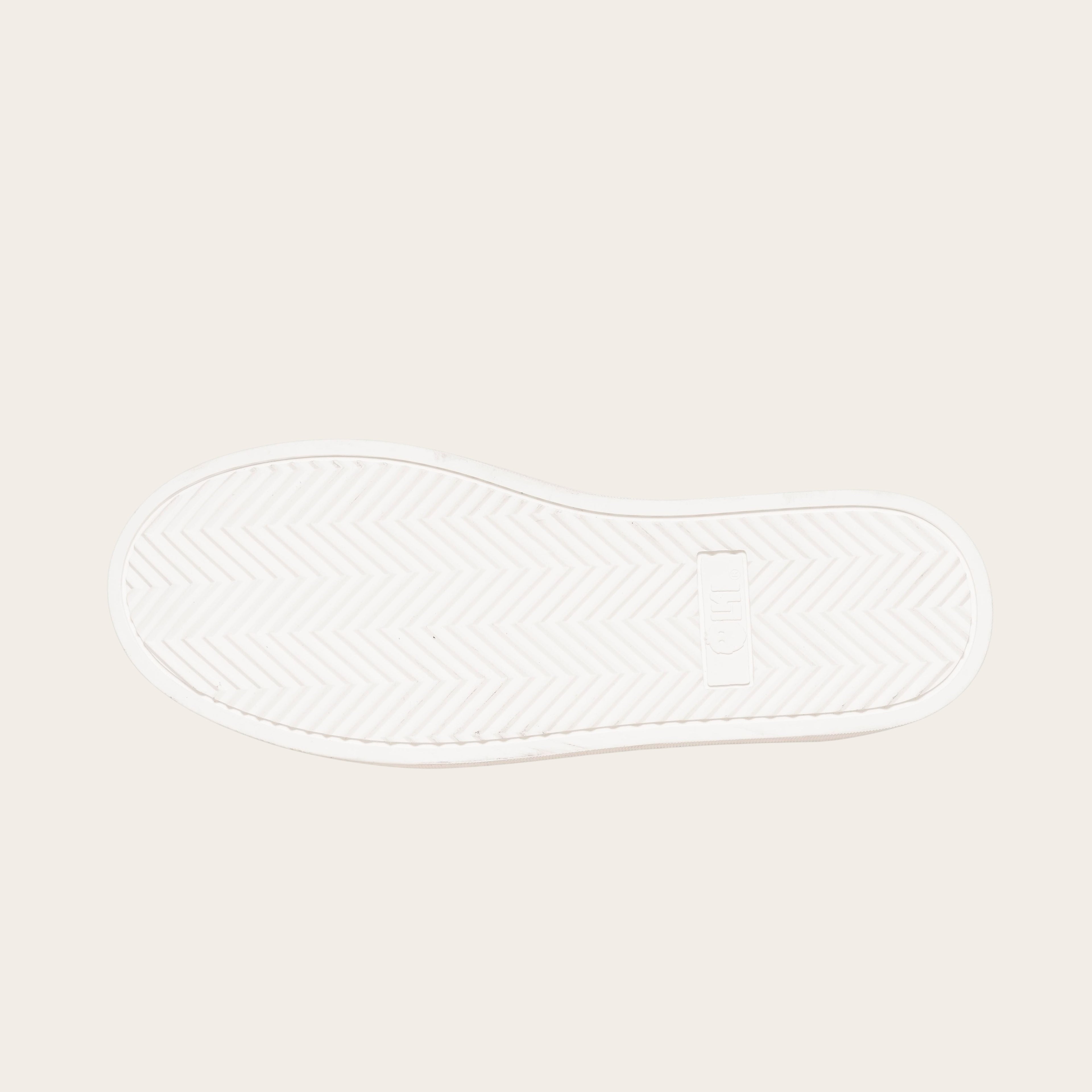 OLKI Zapatilla Nevado blanca planta de caucho antideslizante con patrón de espiga y logo. Diseño urbano.