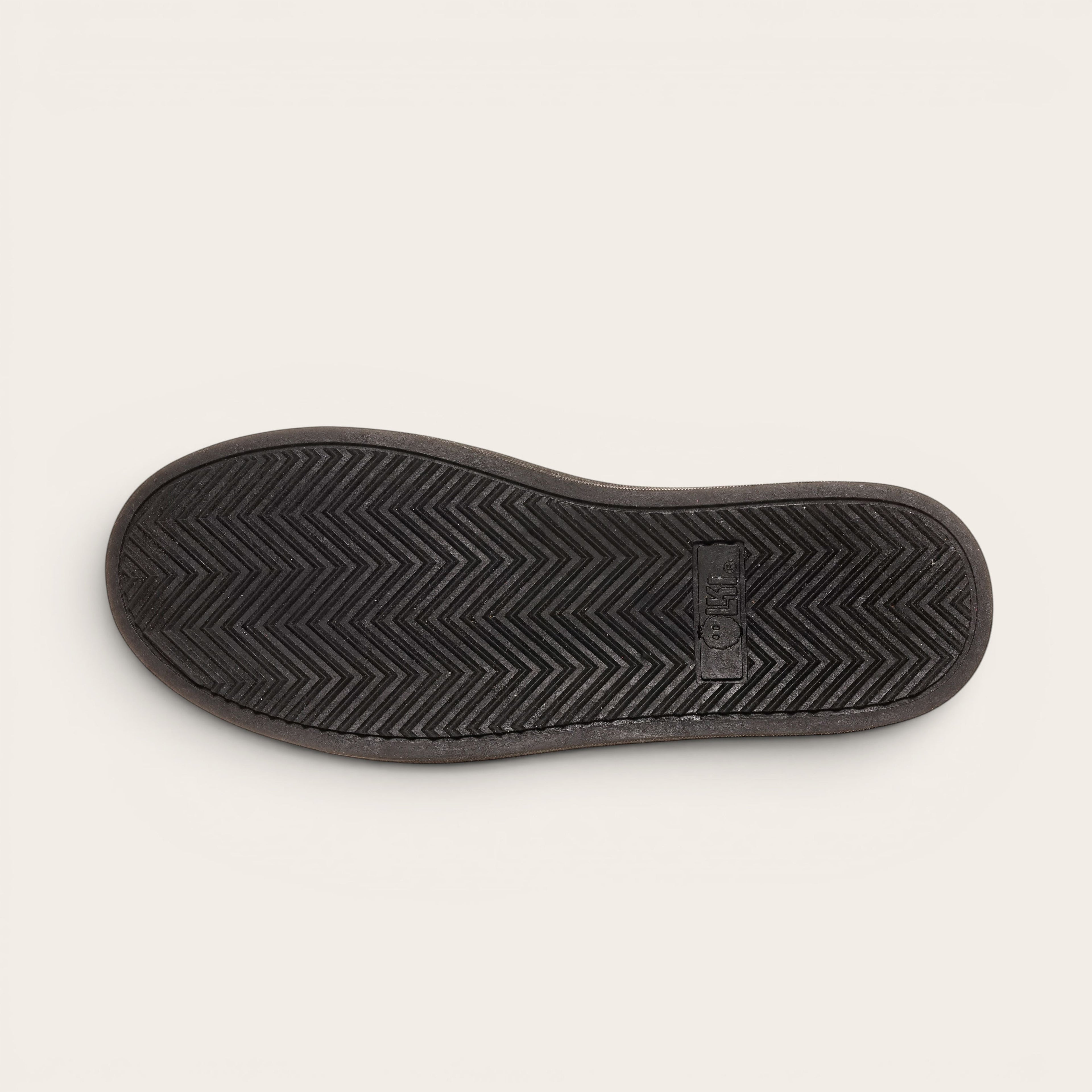Zapatilla OLKI Nevado negra de cuero con talonera blanca y planta de caucho antideslizante.