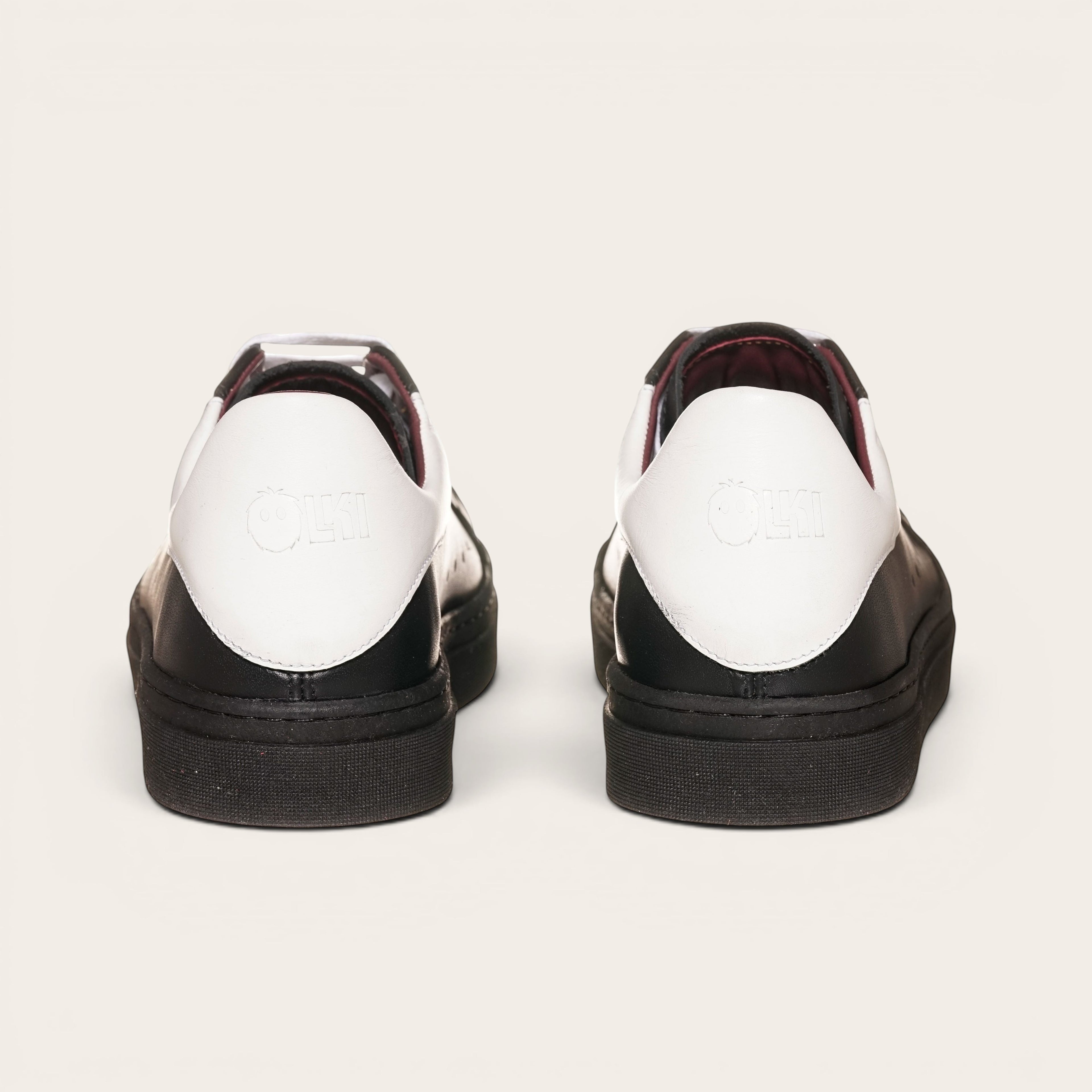 Zapatillas OLKI Nevado negras de cuero con talonera blanca y detalles en burdeos. Diseño artesanal chileno.