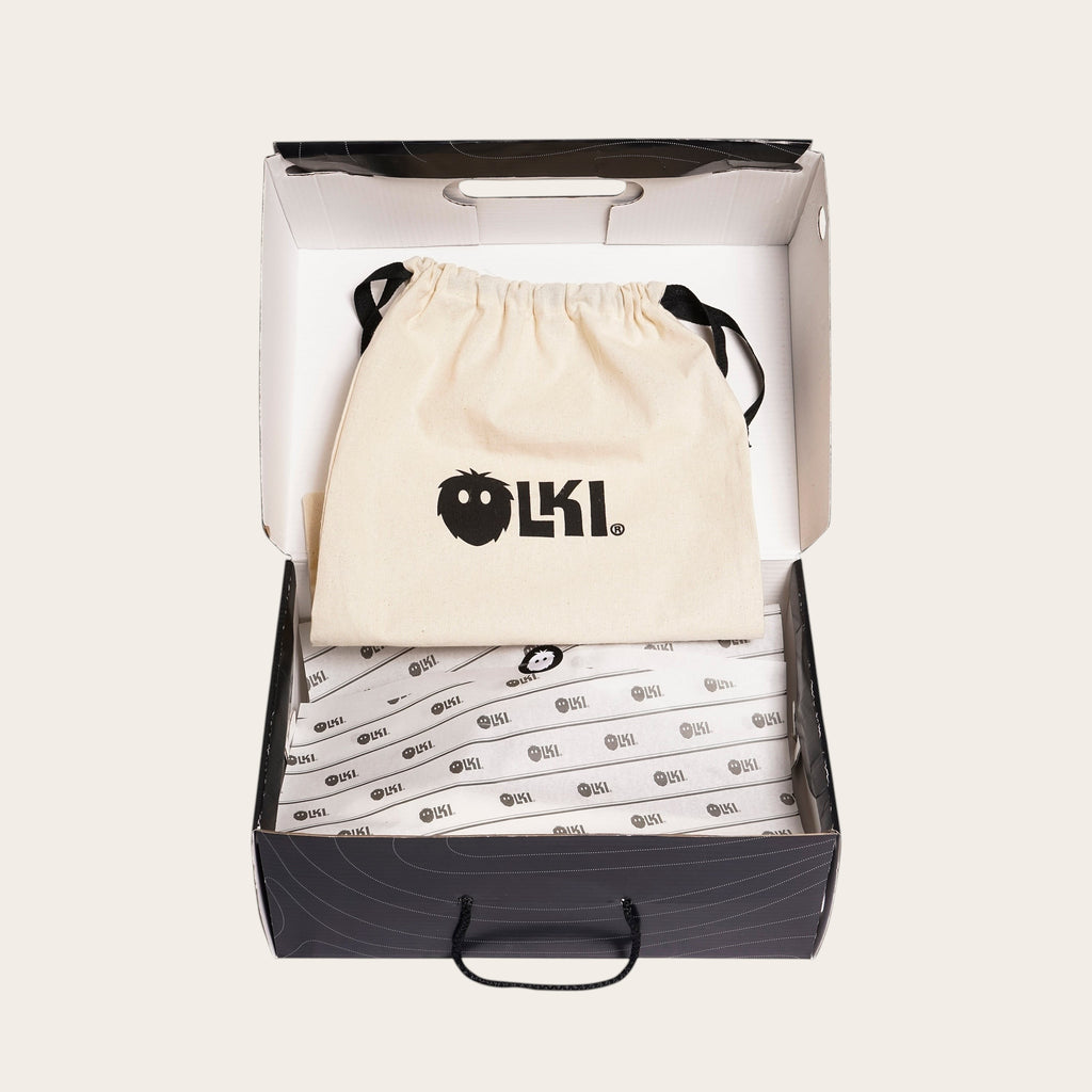 OLKI Zapatilla Nevado Negra, zapatilla de cuero negro con talonera negra, forro de cuero guinda y planta de caucho antideslizante. Presentada en su caja con bolsa protectora.