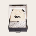 OLKI Zapatilla Nevado Negra, zapatilla de cuero negro con talonera negra, forro de cuero guinda y planta de caucho antideslizante. Presentada en su caja con bolsa protectora.