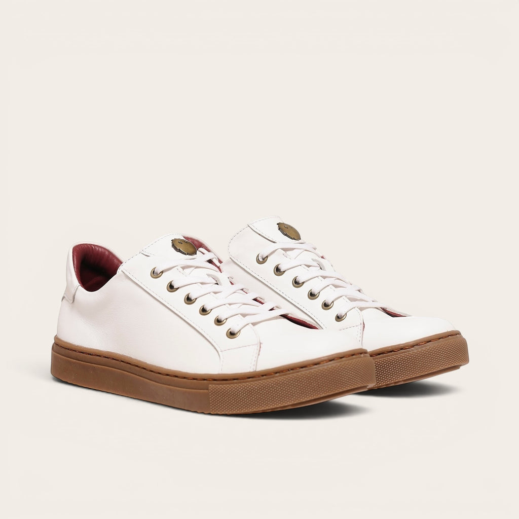 Zapatilla blanca de cuero de vacuno de OLKI con planta de caucho marrón y forro guinda. Diseño clásico con cordones.